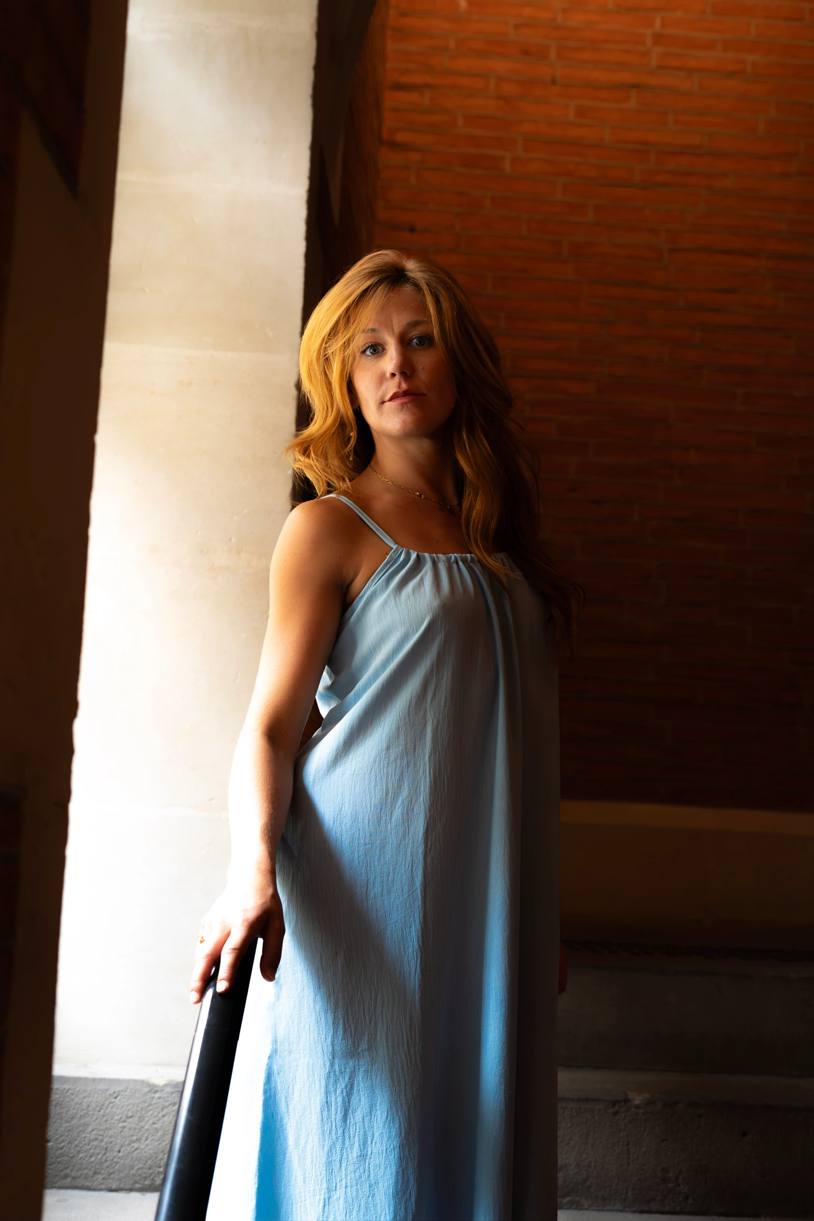 Élodie Ménadier en robe bleue, près d’une fenêtre